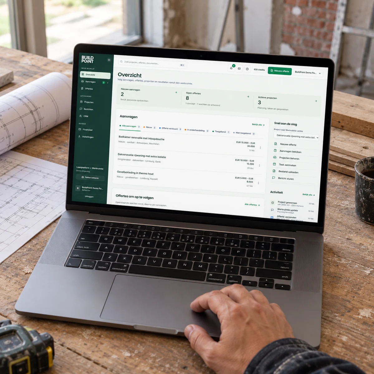 Laptopmockup met het vernieuwde BuildPoint Pro-dashboard op een werkbank tijdens een renovatie.